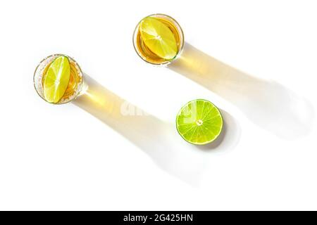 Doses de Tequila avec des bords salés et des tranches de citron vert, grenaille à plat au-dessus Banque D'Images