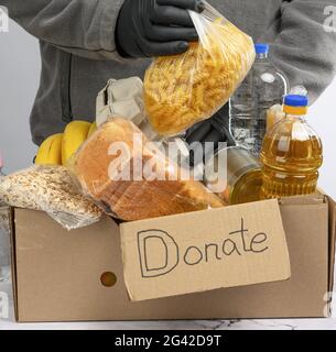 Recueille la nourriture, les fruits et les choses dans une boîte en carton pour aider les nécessiteux et les pauvres Banque D'Images