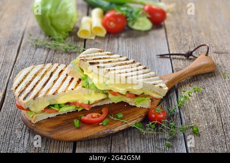 Panini pressé végétarien avec légumes et fromage servi sur un plan de découpe en bois Banque D'Images