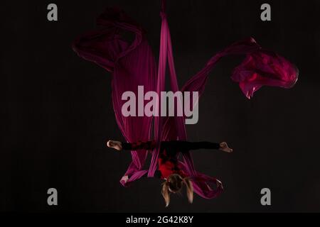 Danseuse en adolescence qui interprète une danse acrobatique sur des silks aériens Banque D'Images