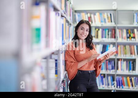 L'étudiant utilise un bloc-notes et une bibliothèque scolaire Banque D'Images