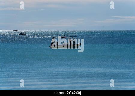 Dingo Beach, Queensland, Australie - juin 2021 : pêcheurs en petits bateaux arrivant à terre par une journée ensoleillée avec un océan bleu et un ciel nuageux Banque D'Images