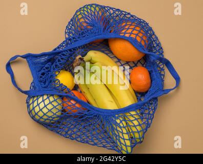 Fruits frais mûrs dans un sac à ficelle textile sur fond marron Banque D'Images