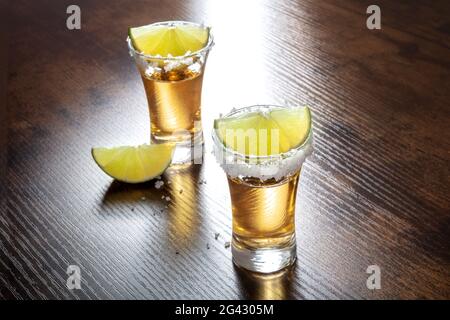 Doses de Tequila avec des bords salés et des tranches de lime Banque D'Images