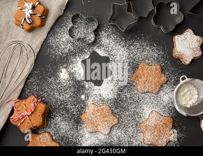 Biscuits cuits au pain d'épice en forme d'étoile saupoudrés de sucre en poudre une table noire Banque D'Images