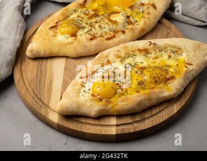 Khachapuri adjarien cuit au four avec jaune d'œuf entier sur panneau de bois, plat traditionnel Banque D'Images