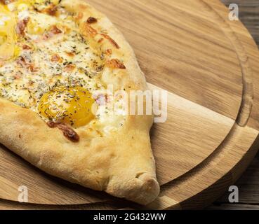 Khachapuri adjarien cuit au four avec du jaune d'œuf entier sur une planche en bois Banque D'Images