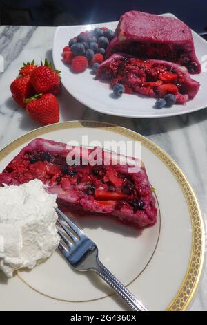 Une tranche d'une terrine maison de pudding anglais d'été avec de la crème fouettée fraîche chattily. Banque D'Images