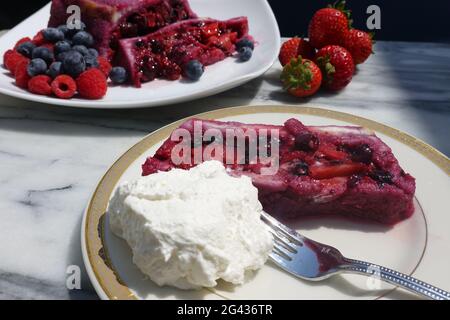 Une tranche d'une terrine maison de pudding anglais d'été avec de la crème fouettée fraîche chattily. Banque D'Images