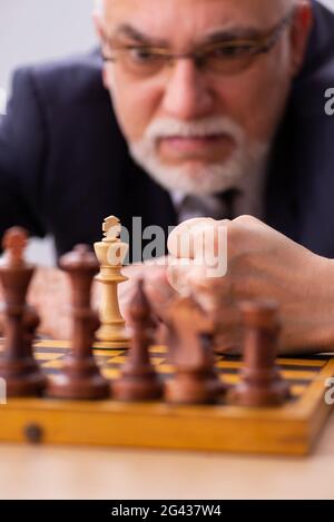 Un vieil employé de sexe masculin joue aux échecs sur le lieu de travail Banque D'Images