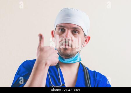 Portrait de jeune médecin avec le pouce vers le haut dans bleu costume de chirurgien isolé Banque D'Images