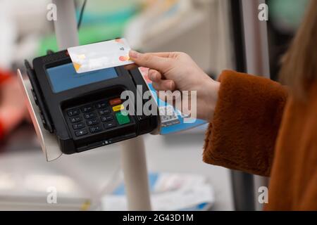 Une jeune femme avec une carte de crédit paie ses achats au comptoir de caisse du magasin. Banque D'Images