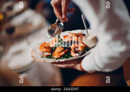 Le serveur sert des crevettes avec des arugula. Banque D'Images