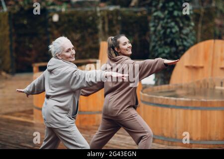 Les femmes faisant des exercices de sport et de remise en forme à l'extérieur. Jeune et âgée femme se réchauffant et yoga au glamping. Mère et da Banque D'Images