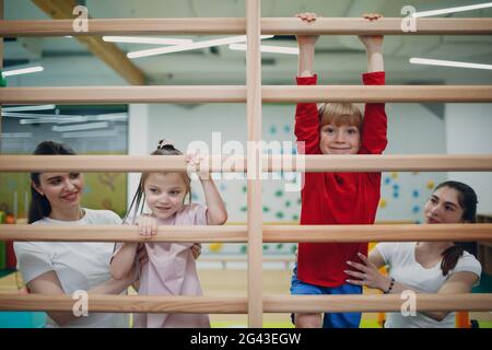 Les enfants font des exercices muraux suédois en salle de gym à la maternelle ou à l'école primaire. Concept de sport et de fitness pour enfants. Banque D'Images