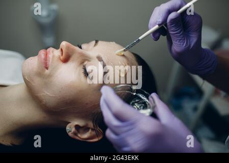 Esthéticienne appliquant avec le gel d'hydrogénation froide de contact de brosse sur le visage de la femme pour les procédures de matériel dans le spa de beauté Banque D'Images