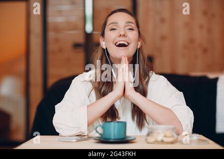 L'application d'écran affiche une jeune femme souriante s'asseoir à table avec un ordinateur portable et parler en vidéo avec un ami ou un collègue, une fille heureuse Banque D'Images