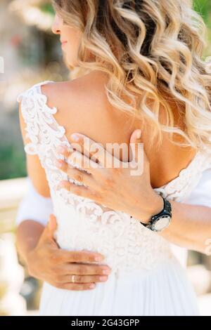 Le marié épouse fermement, les mains du marié à l'arrière de la mariée Banque D'Images