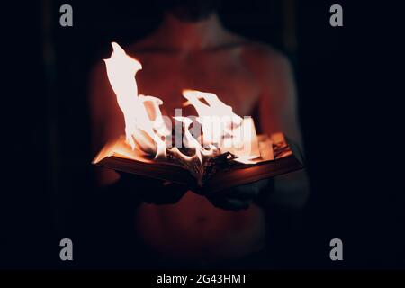 L'homme tient le livre brûlant dans ses mains. Banque D'Images