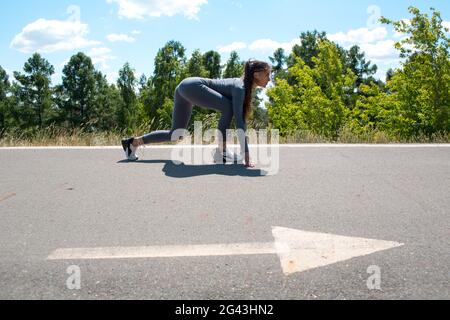Une femme sportive sur la piste commence à courir. Fille de jogging. Direction de la flèche. Banque D'Images