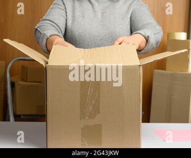 Une femme dans un chandail gris est d'emballer des boîtes en carton brun sur une table blanche Banque D'Images