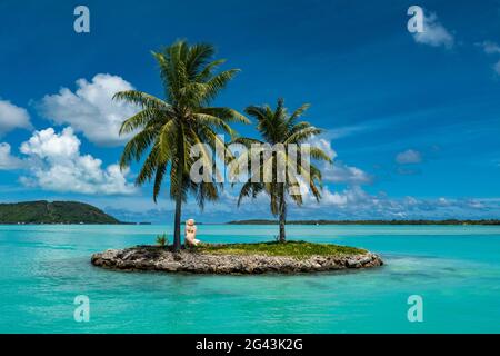 Deux palmiers et une sculpture tiki sur une petite île à l'entrée du port de l'aéroport de Bora Bora (BOB), Bora Bora, îles Leeward, Polyn français Banque D'Images