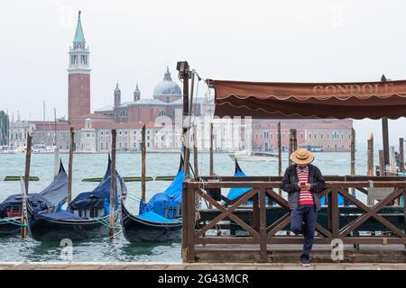 Vue sur les gondoles vénitiennes et un gondolier sur la place Saint-Marc, en arrière-plan l'île de San Giorgio, Venise, Vénétie, Italie, Europe Banque D'Images