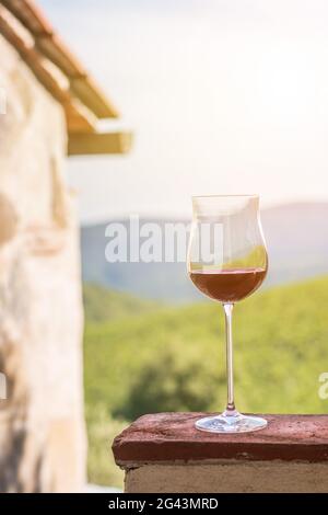 Verre de vin rouge en Toscane. Vignobles en arrière-plan. Soleil. Banque D'Images