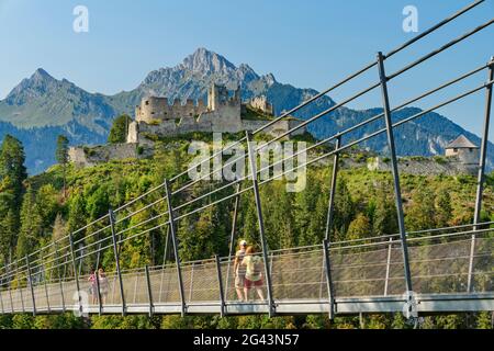 Plusieurs personnes se promènent sur le pont de corde Highline 179 avec les ruines du château d'Ehrenberg en arrière-plan, Reutte, Tyrol, Autriche Banque D'Images