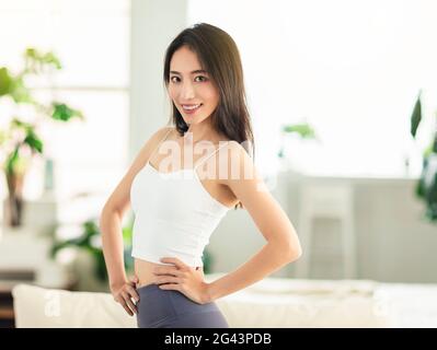 jeune femme avec ses bras akimbo, prête à faire de la forme physique et de l'exercice à la maison, et regarde avec confiance Banque D'Images