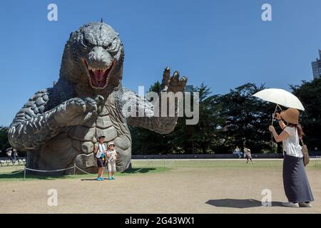 Une japonaise photographie ses enfants devant un grand modèle de Godzilla dans un parc derrière le complexe de Tokyo Midtown, Roppongi, Tokyo, Japon. Banque D'Images