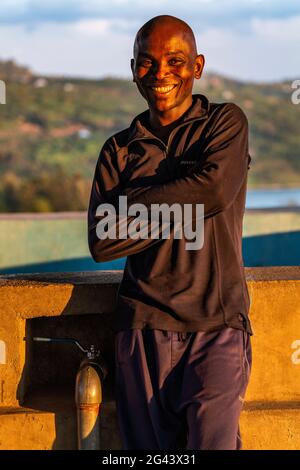Portrait d'un homme rwandais souriant dans la lumière de la fin de l'après-midi, Kinunu, province occidentale, Rwanda, Afrique Banque D'Images