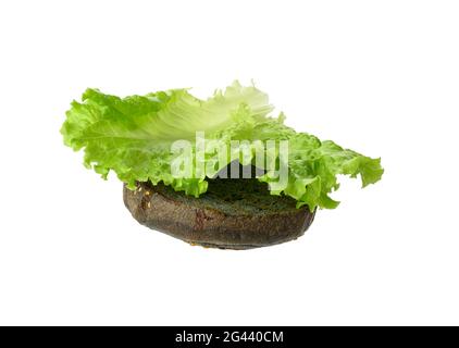 La feuille de laitue verte repose sur la moitié d'un petit pain rond noir Banque D'Images