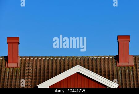 Vue d'une maison suédoise rouge contre un ciel bleu avec 2 cheminées, Grimsholmen, Halland, Suède Banque D'Images
