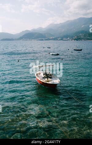 Le petit bateau est ancré près du rivage par une journée ensoleillée. Sur fond de montagnes et de mer Banque D'Images