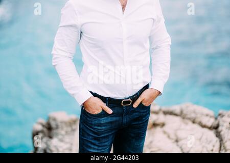 L'homme est debout sur une plage rocheuse avec ses mains dans les poches Banque D'Images