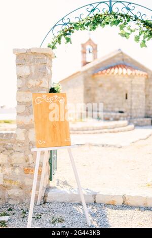 Chevalet en bois vide avec des monogrammes se tient à une porte voûtée mêle ivy Banque D'Images