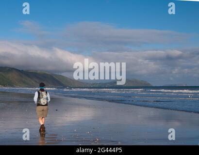 Une femme d'âge moyen (62 ans) en train de marcher le long de Raumati Beach, en Nouvelle-Zélande Banque D'Images