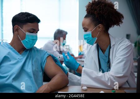 Race mixte couple de médecins portant des masques faciaux faisant l'injection Banque D'Images