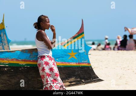 Jeune femme penchée sur un bateau de pêche sur la plage de Morondava, Madagascar, Afrique Banque D'Images