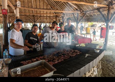 L'équipage de cuisine du cargo de passagers Aranui 5 (Aranui Cruises) prépare un barbecue de plage pour les clients sur un îlot Motu privé dans le lagon de Bora B. Banque D'Images