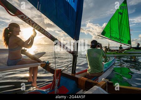 Les gens aiment la voile sur un canoë-outrigger au coucher du soleil avec une vue sur l'île de Moorea, près de Papeete, Tahiti, les îles du vent, Polynésie française, Sud Banque D'Images