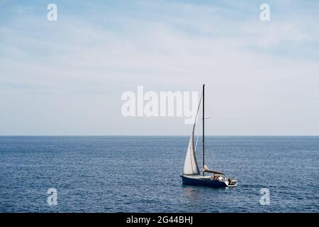 Petit bateau avec une voile blanche flottant dans le vent voiles sur la mer Banque D'Images