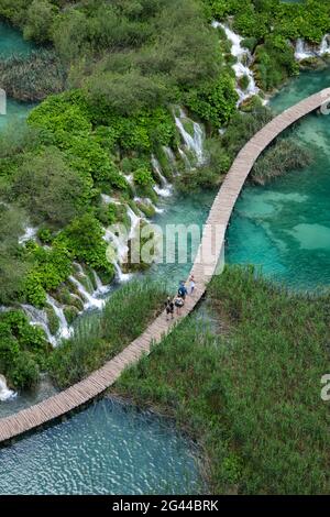 Vue sur les gens sur le chemin de bois en bois au-dessus de la piscine avec des cascades, Parc national des lacs de Plitvice, Lika-Senj, Croatie, Europe Banque D'Images