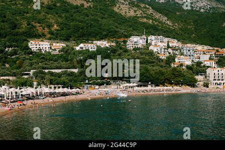 Vue sur la plage avec chaises longues et parasols en arrière-plan de la ville antique près de l'île de Sveti Stefan à Monte Banque D'Images