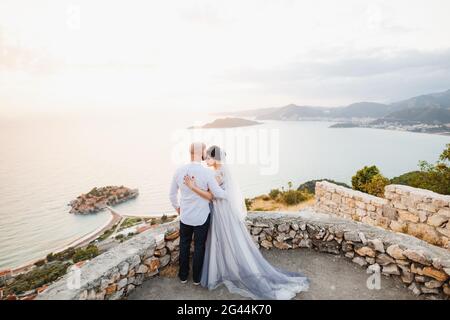 La mariée et le marié s'embrassent sur la terrasse d'observation Vue sur l'île de Sveti Stefan Banque D'Images