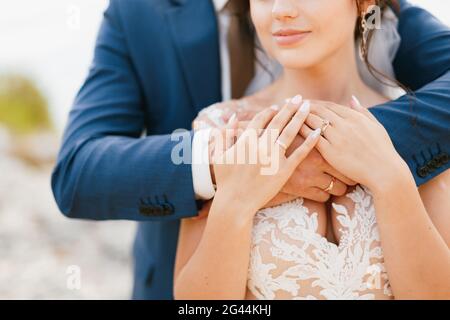 Le marié épouse doucement la mariée par les épaules, la mariée a mis ses mains sur les bras du marié, gros plan Banque D'Images