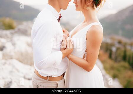La mariée et le marié s'embrassent entre les montagnes tenant les mains et regarde l'un l'autre, gros plan Banque D'Images
