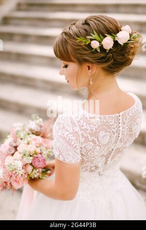 Mariée douce avec un bouquet de mariage dans ses mains et fleurs dans ses cheveux debout sur les escaliers anciens de Le temple de Prcanj Banque D'Images