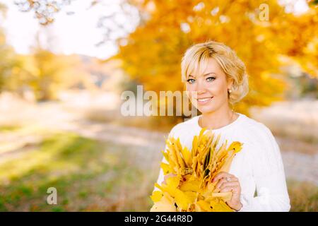 Demi portrait de belle femme tenant un bouquet de jaune feuilles Banque D'Images